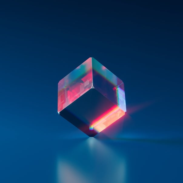 An image of a glass cube standing on one of its vertices. Blue background and light refracting from the cube